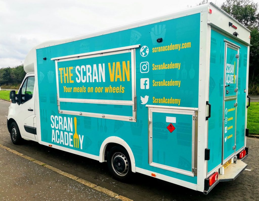 a turquoise van with the name 'The Scran Van' written across the side
