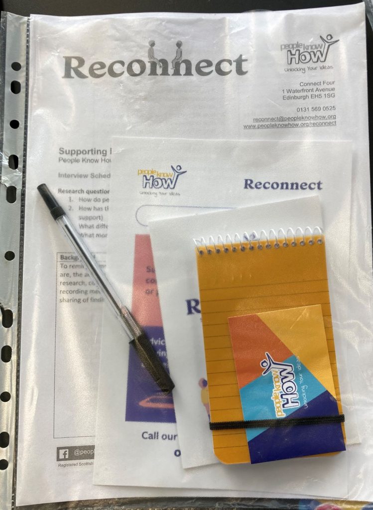 A pen, papers, and notebook from People Know How's Reconnect service are contained within a transparent folder